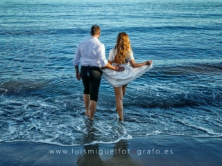 Foto de postboda atrevida y original con novios en la playa entrando en el agua
