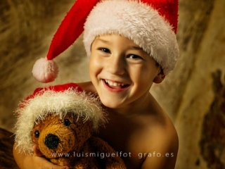 Ni&ntilde;o sonriendo con osito de papa noel