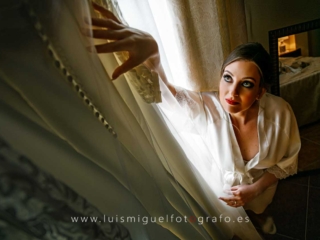 Novia en bata acariciando su vestido de boda