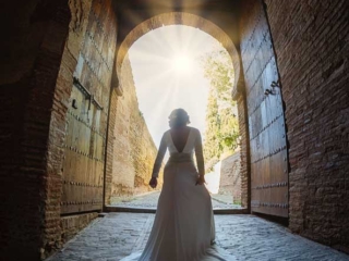 foto de postboda con novia en la puerta de la alhambra iluminada por los rayos del sol