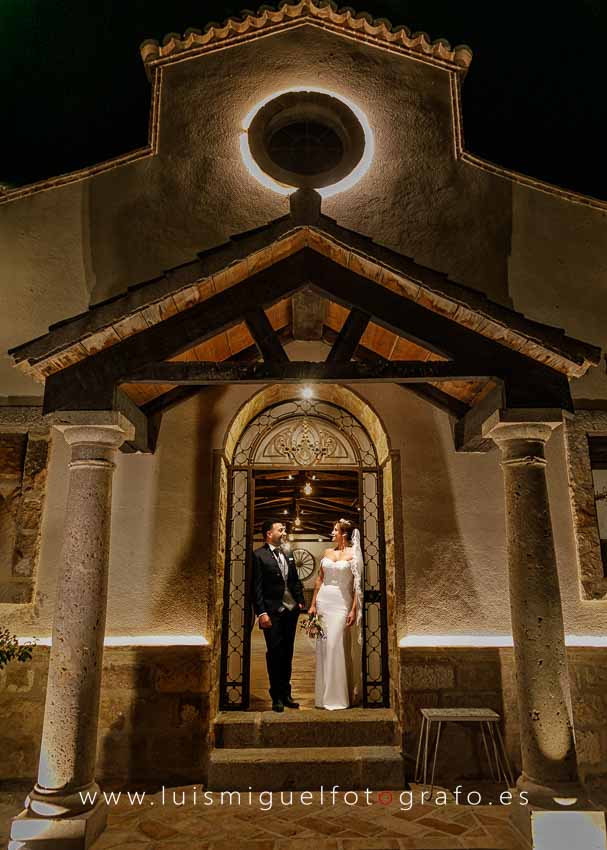 Retrato nocturno de novios bajo el pórtico iluminado del Cortijo el Brujuelo
